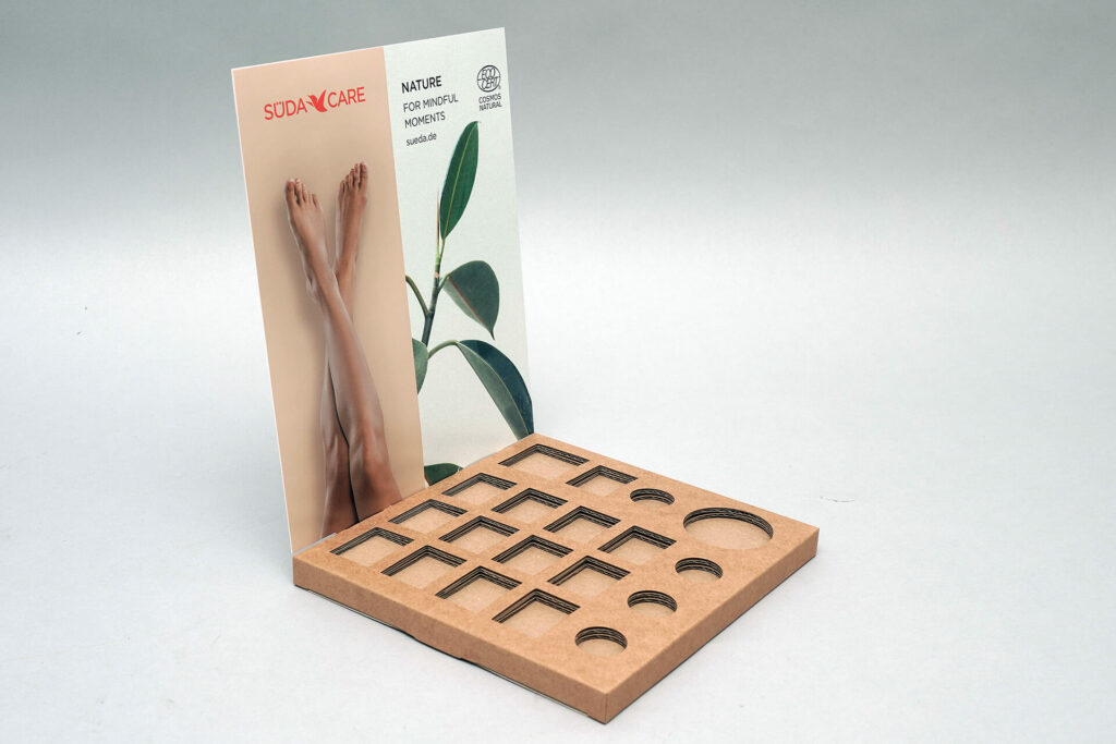 Thekendisplay von pod GmbH für Firma Südacare mit 19 Steckfächern für Produktverpackungen mit teils rechteckigem und teils rundem Boden