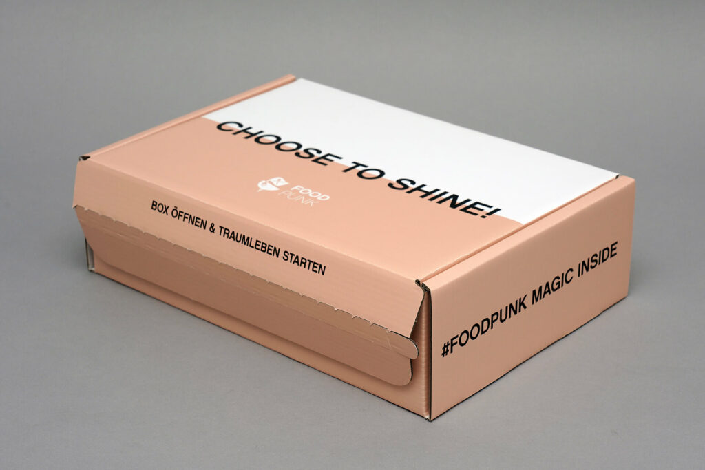 Flache Versandverpackung von pod GmbH für Firma Food Punk auf grauem Untergrund