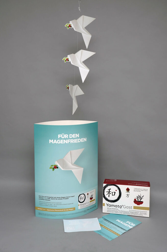 Schaufensterdekoration von pod GmbH für das Medikament YamatoGast - einem Mobile, einem Aufsteller mit ovaler Grundform und der Aufschrift "Für den Magenfrieden" und der rechteckigen Verpackung des Medikaments